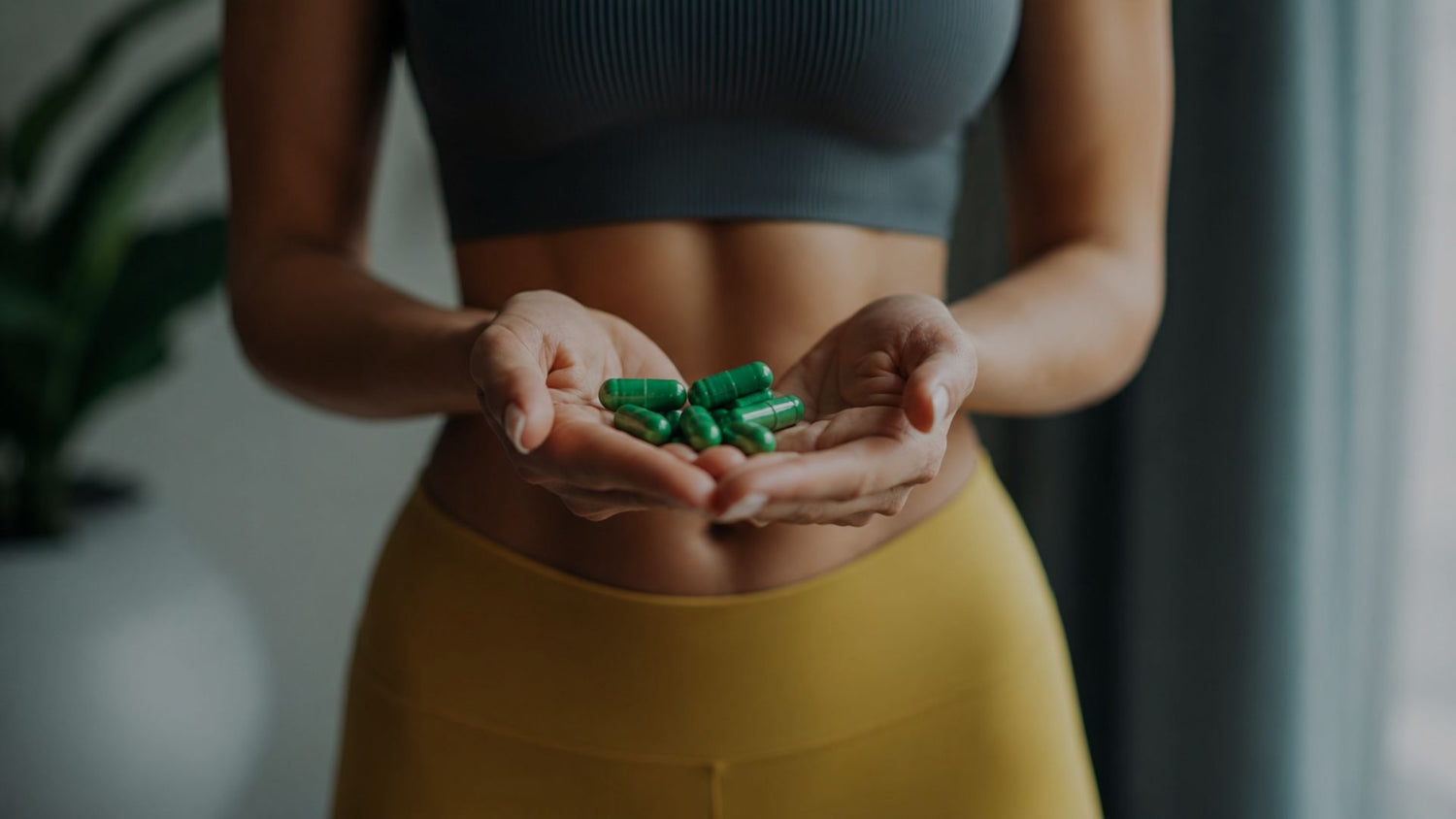 Person holding green capsules in their hands with a neutral background