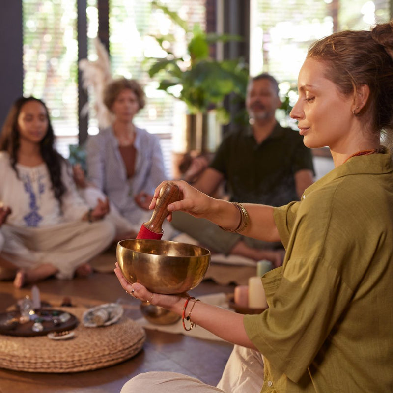 Woman holding a singing bowl in a group setting with blurred people in the background
